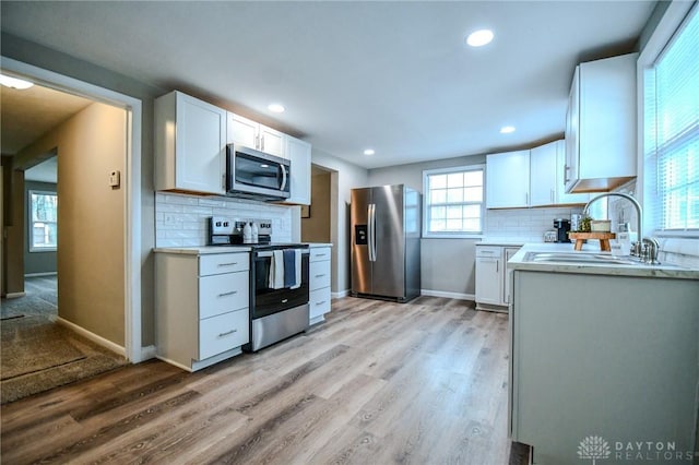 2004 N Reardon Dr, Dayton, OH 45420 - kitchen featuring light wood-style flooring, a sink, light countertops, white cabinets, and appliances with stainless steel finishes