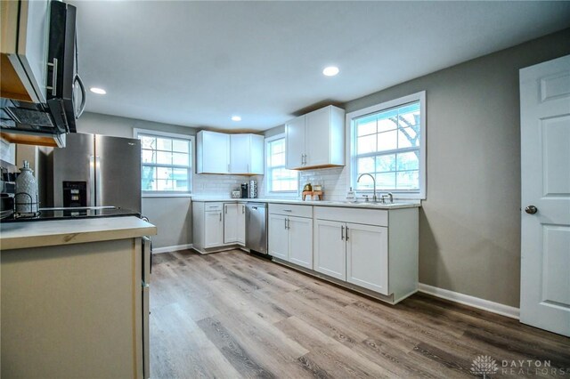 2004 N Reardon Dr, Dayton, OH 45420 - kitchen featuring a sink, tasteful backsplash, light wood-style floors, and appliances with stainless steel finishes