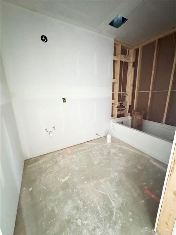 bathroom featuring unfinished concrete floors and a bath