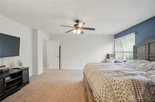bedroom featuring light colored carpet, baseboards, and a ceiling fan