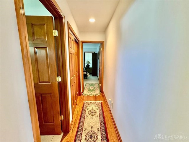 hallway with baseboards, light wood-type flooring, and recessed lighting