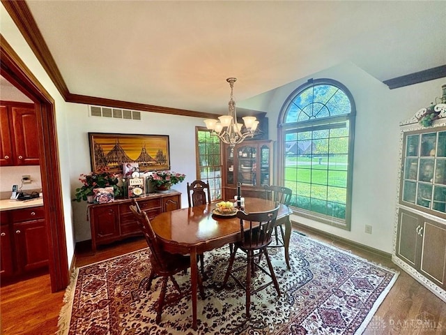 dining space with ornamental molding, baseboards, visible vents, dark wood-style flooring, and a notable chandelier