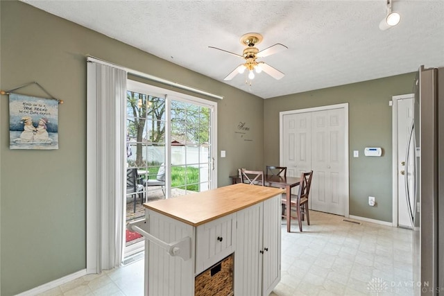 1579 Commonwealth Dr, Xenia, OH 45385 - kitchen with light flooring, stainless steel refrigerator, ceiling fan, white cabinetry, and a kitchen island