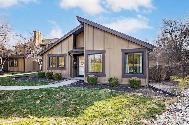 mid-century inspired home with a front yard, a chimney, and board and batten siding