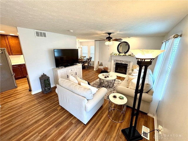 living room with baseboards, ceiling fan, visible vents, and wood finished floors