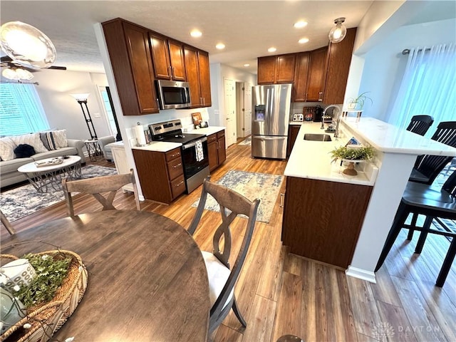 kitchen with a peninsula, a breakfast bar, a sink, stainless steel appliances, and light countertops