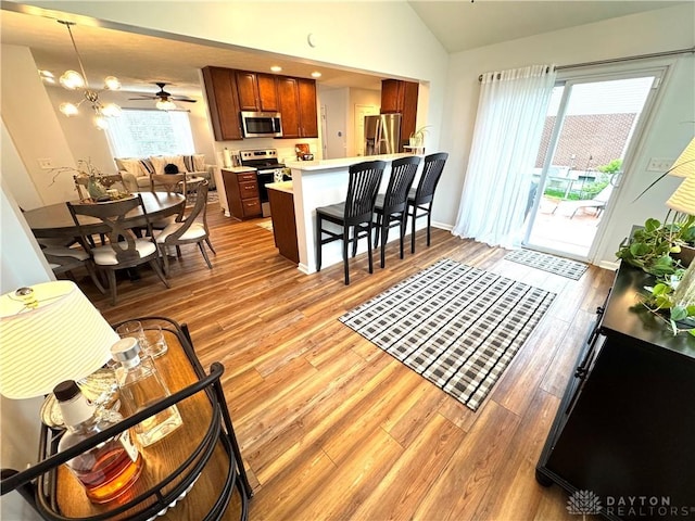 living room featuring a ceiling fan, light wood-style floors, and lofted ceiling