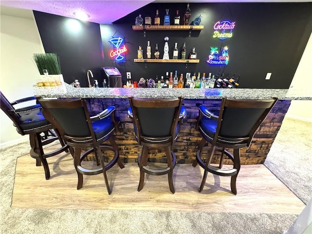 bar featuring wet bar, wood finished floors, baseboards, and carpet floors