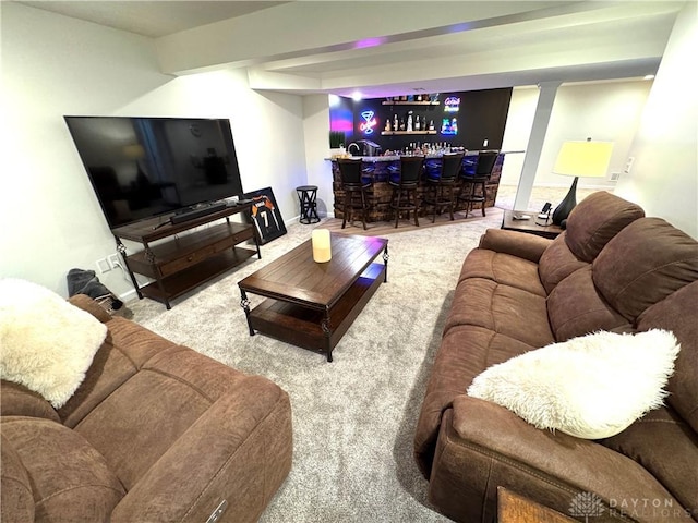 carpeted living area with a bar and baseboards