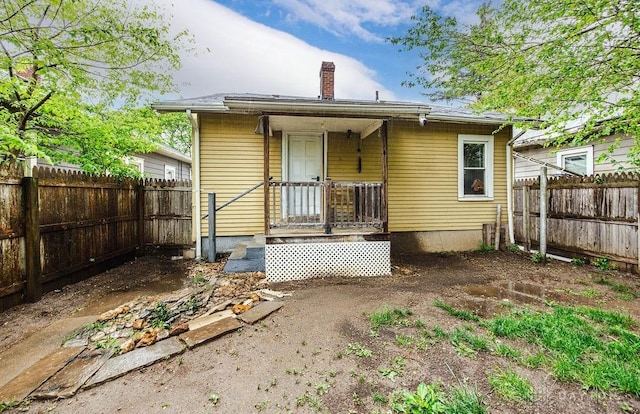 rear view of house featuring a fenced backyard and a chimney