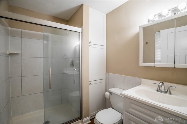 5149 Marshall Rd, Washington Twp, OH 45429 - bathroom featuring toilet, a stall shower, vanity, wainscoting, and tile walls