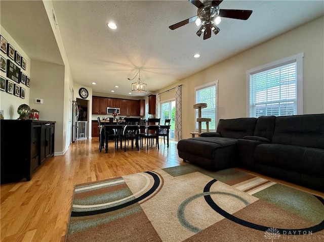 living room featuring a ceiling fan, light wood-style floors, recessed lighting, and a textured ceiling