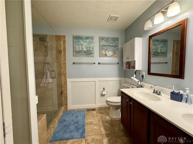 full bath featuring double vanity, a stall shower, a sink, visible vents, and tile patterned flooring