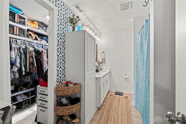 784 Marshall Dr, Xenia, OH 45385 - full bath with a textured ceiling, vanity, wood finished floors, a walk in closet, and baseboards