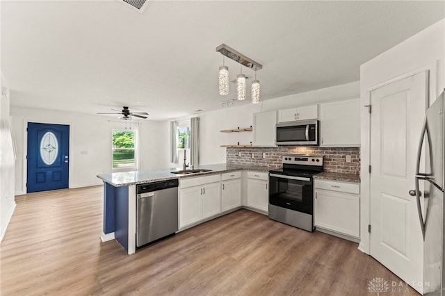 784 Marshall Dr, Xenia, OH 45385 - kitchen featuring stainless steel appliances, a peninsula, white cabinetry, tasteful backsplash, and light wood finished floors