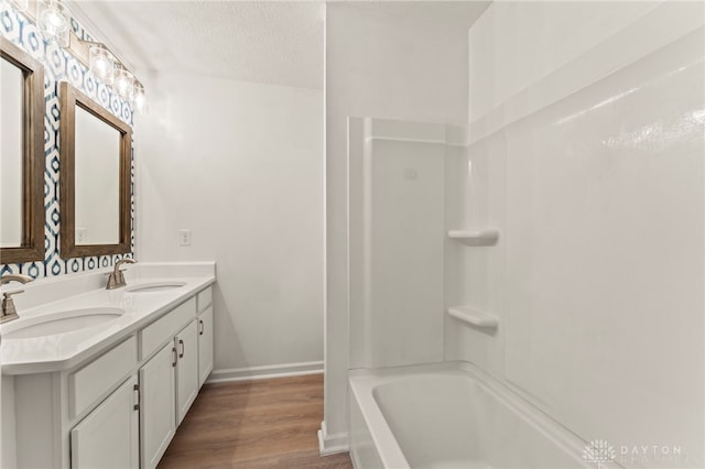 784 Marshall Dr, Xenia, OH 45385 - bathroom featuring double vanity, wood finished floors, shower / washtub combination, and a textured ceiling