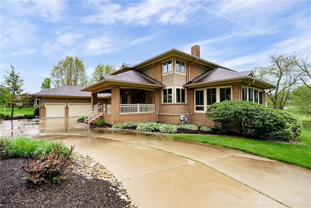 view of front of house featuring covered porch, brick siding, driveway, a garage, and a chimney