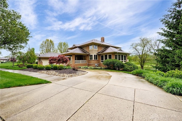 view of front of property featuring concrete driveway, a front lawn, and a chimney