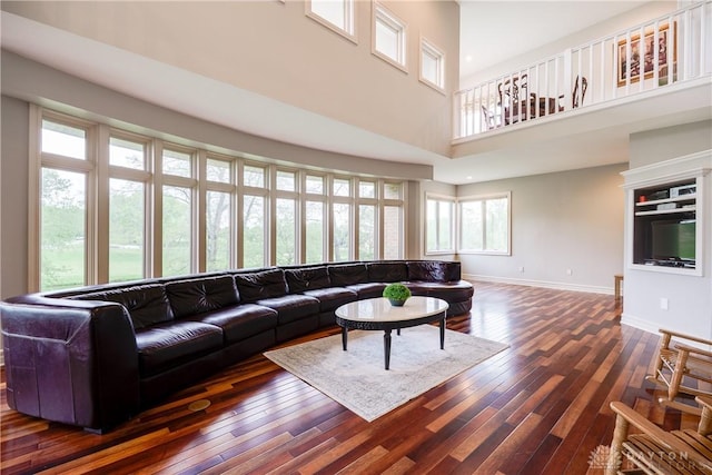 living area featuring dark wood-type flooring, baseboards, and a high ceiling