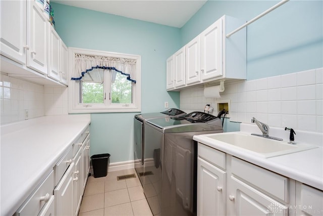 washroom with a sink, cabinet space, light tile patterned flooring, washing machine and clothes dryer, and baseboards