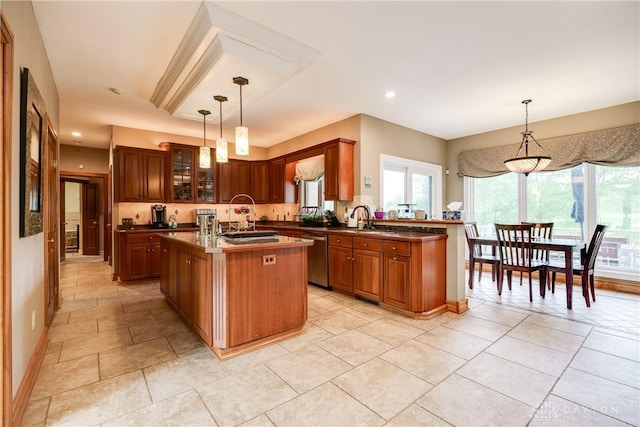 kitchen with a kitchen island with sink, dark countertops, stainless steel dishwasher, and a sink