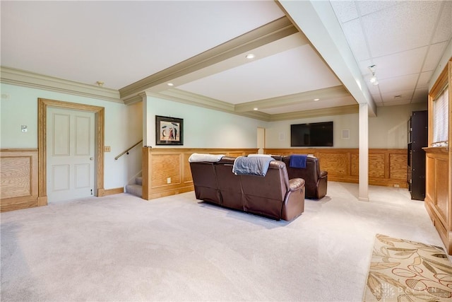 living area with a wainscoted wall, a decorative wall, light colored carpet, ornamental molding, and stairs