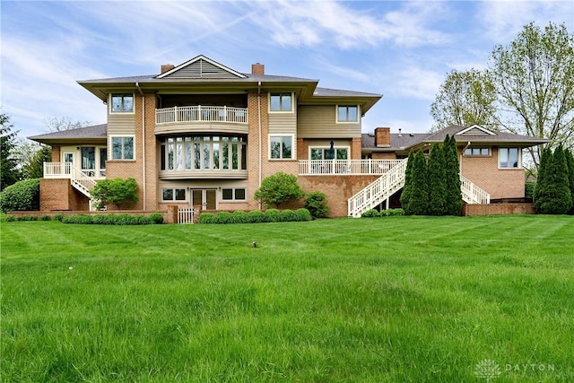 back of house with a yard, stairway, a chimney, and a balcony