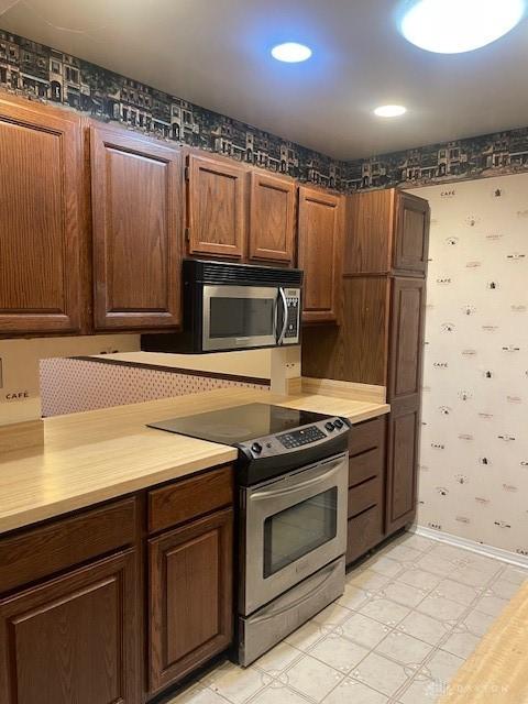 kitchen with stainless steel appliances, baseboards, light countertops, and wallpapered walls