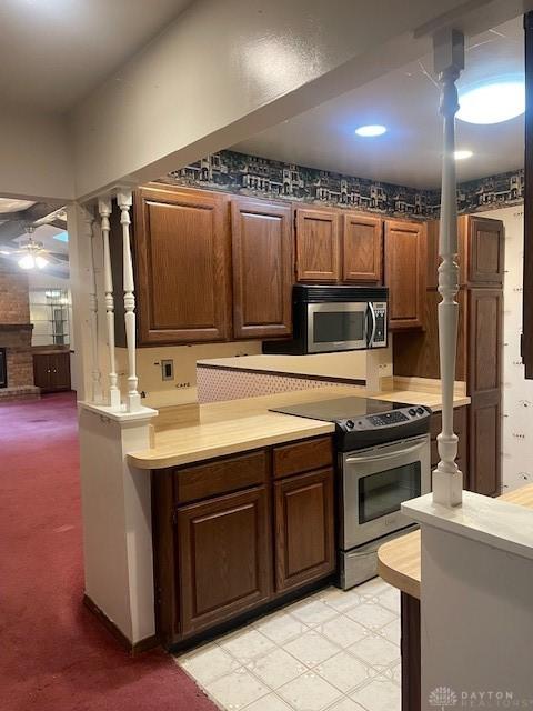 kitchen featuring light countertops, stainless steel appliances, a fireplace, and ceiling fan