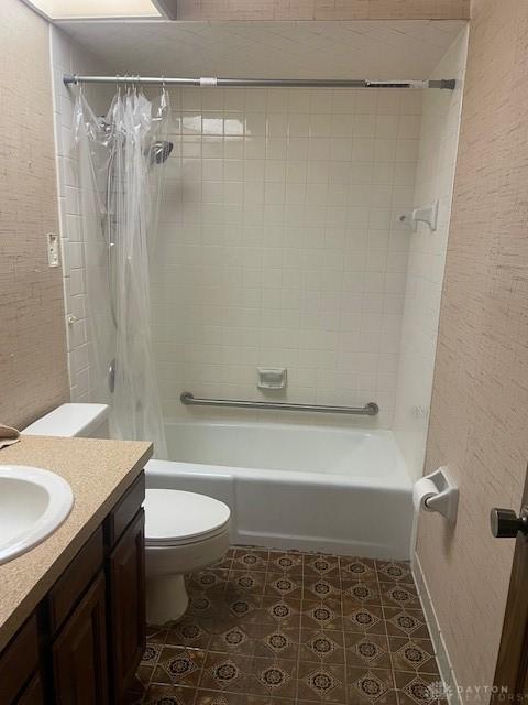 full bath featuring vanity, toilet, a textured wall, and shower / tub combo