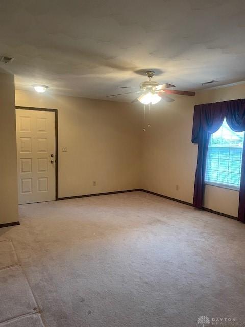 unfurnished room featuring light carpet, baseboards, a ceiling fan, and visible vents