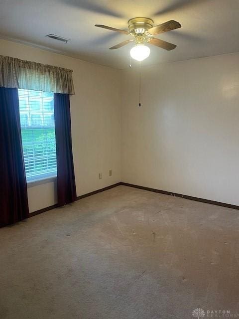 spare room with visible vents, baseboards, a ceiling fan, and light carpet
