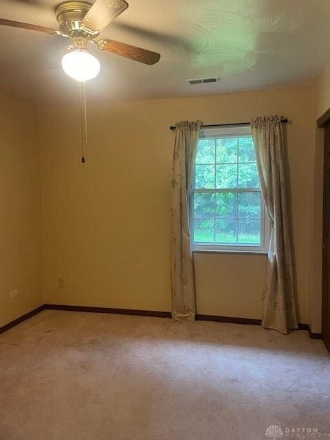 unfurnished room with a ceiling fan, light carpet, visible vents, and baseboards