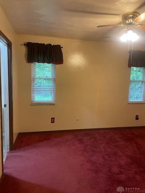 spare room with a ceiling fan and dark carpet