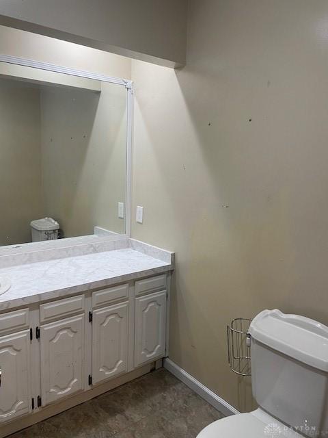 bathroom with toilet, baseboards, and vanity