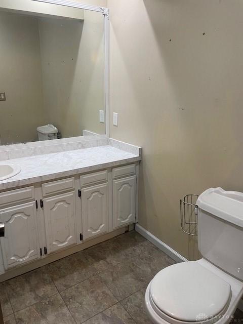 bathroom featuring toilet, baseboards, and vanity