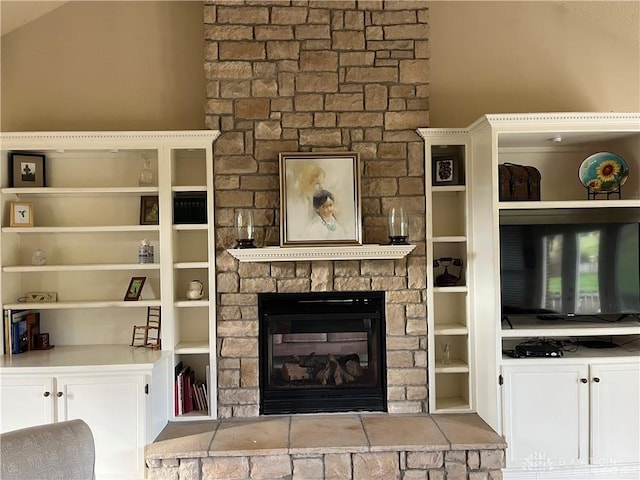 unfurnished living room featuring a stone fireplace and built in shelves