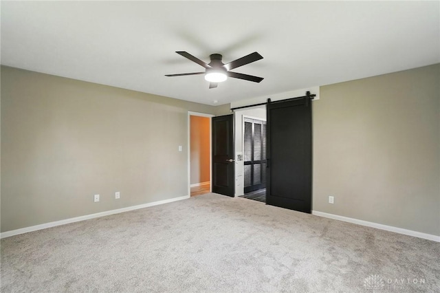 5741 Hithergreen Dr, Washington Twp, OH 45429 - unfurnished bedroom with carpet flooring, a barn door, and a ceiling fan