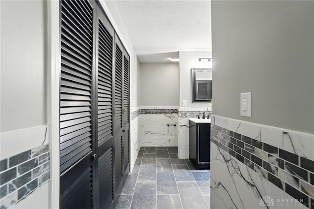 5741 Hithergreen Dr, Washington Twp, OH 45429 - bathroom featuring tile walls, a wainscoted wall, vanity, marble finish flooring, and a closet