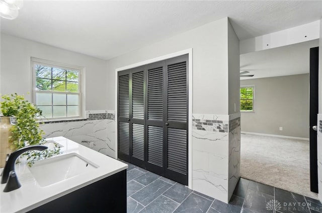 5741 Hithergreen Dr, Washington Twp, OH 45429 - bathroom featuring tile walls, vanity, wainscoting, and ceiling fan