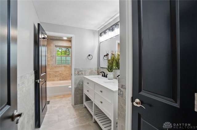 5741 Hithergreen Dr, Washington Twp, OH 45429 - bathroom featuring tile walls, double vanity, a tub to relax in, wainscoting, and tile patterned floors
