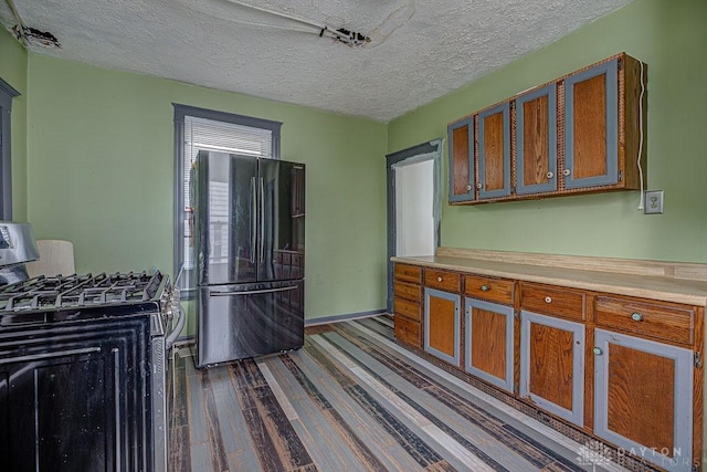 4103 Whetsel Ave, Cincinnati, OH 45227 - kitchen featuring stainless steel range with gas stovetop, freestanding refrigerator, a textured ceiling, brown cabinets, and dark wood-type flooring