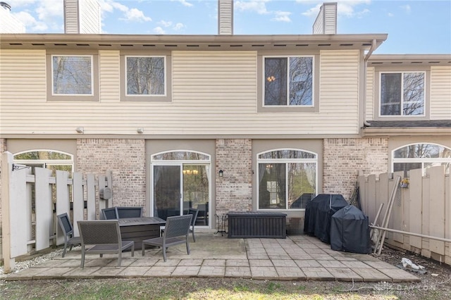 back of house with a fenced backyard, brick siding, and a patio