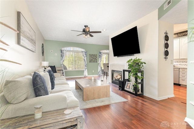 living room with ceiling fan, wood finished floors, a fireplace, and baseboards