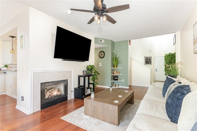 living area with wood finished floors, ceiling fan, and a fireplace
