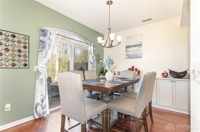 dining area featuring a chandelier, dark wood-type flooring, and baseboards
