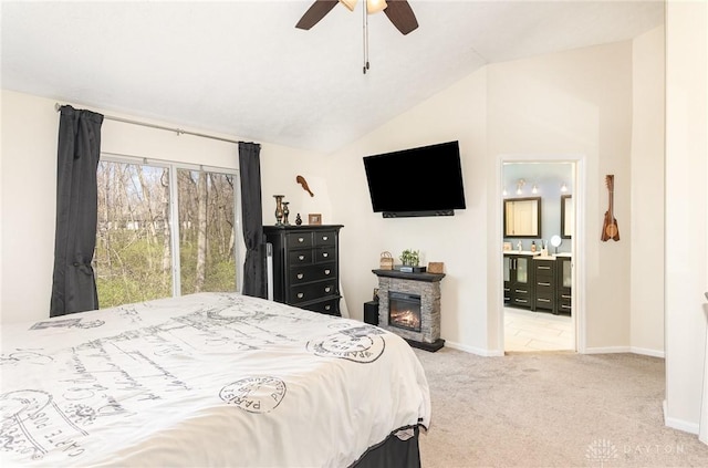 carpeted bedroom featuring lofted ceiling, a fireplace, baseboards, connected bathroom, and ceiling fan