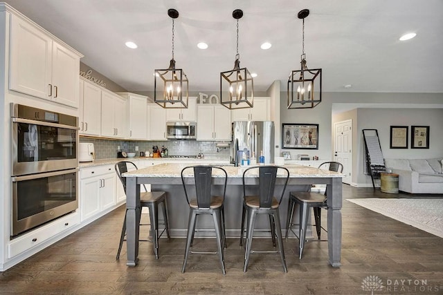 1737 Red Clover Dr, Lebanon, OH 45036 - kitchen featuring appliances with stainless steel finishes, backsplash, white cabinetry, an island with sink, and recessed lighting