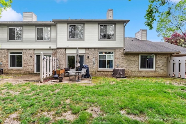 rear view of property with a chimney, brick siding, and a patio area