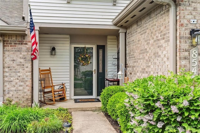 property entrance with brick siding and a porch